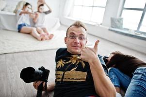 il team di due fotografi che riprende le gemelle in studio mentre realizzano le proprie maschere color crema. fotografo professionista al lavoro. l'uomo soddisfatto mostra il pollice in su. foto