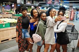 gruppo di cinque donne africane che fanno selfie per telefono al supermercato. foto