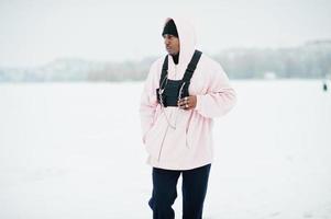 elegante uomo afroamericano in stile urbano con felpa con cappuccio rosa posato sul lago ghiacciato in inverno. foto