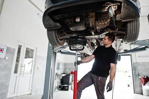 tema riparazione e manutenzione auto. meccanico in uniforme che lavora in servizio auto. foto