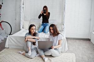giovane ragazza fotografo che spara in studio due gemelle che stanno guardando il laptop. fotografo professionista al lavoro. foto