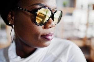 volto ravvicinato di una ragazza afroamericana in occhiali da sole poste al caffè moderno. foto