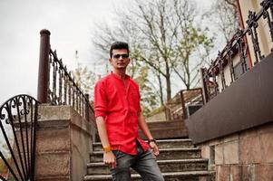 uomo indiano in camicia rossa e occhiali da sole poste all'aperto. foto
