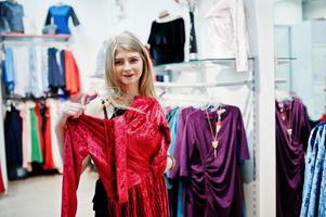 ragazza bionda prova un vestito rosso nella boutique. foto