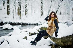 eleganza ragazza riccia in pelliccia al parco forestale innevato in inverno. foto