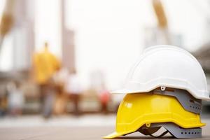 cappello da casco di sicurezza bianco, giallo per il progetto di sicurezza di un operaio come ingegnere o lavoratore, su pavimento di cemento in città
