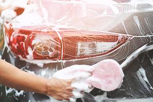 persone uomo che tiene la mano spugna rosa per lavare l'auto. concetto di autolavaggio pulito. foto