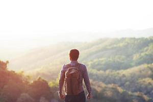 uomo che fa un'escursione alle montagne del tramonto con lo zaino pesante stile di vita di viaggio voglia di viaggiare concetto di avventura estate foto