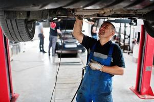 tema riparazione e manutenzione auto. meccanico in uniforme che lavora in servizio auto. foto