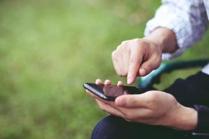 il giovane indossa una camicia a quadri. mano ravvicinata utilizzando il telefono cellulare durante il riposo sul divano. seduto a guardare il messaggio sullo smartphone mobile durante la pausa relax. focalizzazione morbida. foto