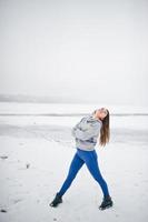 ragazza divertente indossare su maglione con cappuccio e jeans, al lago ghiacciato in una giornata invernale. foto