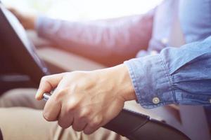 primo piano della giovane donna che tira la leva del freno a mano in auto per sicurezza durante il parcheggio. foto