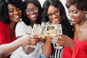 gruppo di ragazze africane in festa che tintinnano bicchieri con champagne spumante. foto