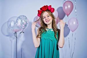 ragazza felice in abito turchese verde e corona con palloncini colorati isolati su bianco. festeggiare il tema del compleanno. foto