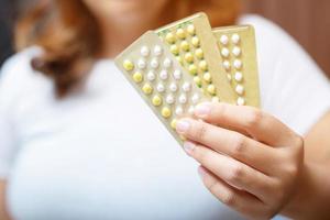 mani della donna che aprono le pillole anticoncezionali in mano. mangiare pillola contraccettiva. foto