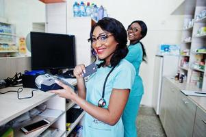 due farmacisti afroamericani che lavorano in farmacia presso la farmacia dell'ospedale. assistenza sanitaria africana. lavorare con terminale di pagamento e carta di credito. foto