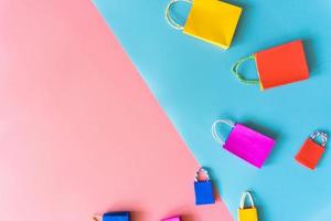 il concetto di shopping online minimo, la borsa della spesa in carta colorata scende da uno sfondo rosa e blu fluttuante per lo spazio della copia. il cliente può acquistare tutto da casa e il corriere consegnerà. foto