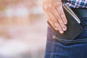 uomo fiducioso che posa in salva mantenendo il portafoglio nella tasca posteriore dei suoi pantaloni con tasca posteriore jean. foto