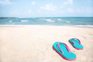 pantofola del piede in scarpe sandali e distribuzione dell'acqua delle onde dell'oceano blu sulla spiaggia sabbiosa bianca, sfondo del mare. il colore dell'acqua e splendidamente luminoso. concetto di estate vacanza natura viaggio. foto