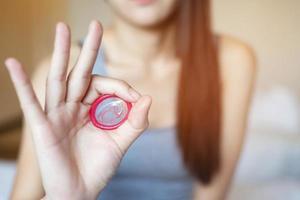 preservativo pronto per l'uso in mano femminile, dare al preservativo un concetto di sesso sicuro sul letto per prevenire l'infezione. foto