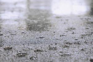 gocce di pioggia nell'acqua pesanti sull'asfalto tonalità di ombra nera e riflesso del cielo scuro in città. alto contrasto durante l'autunno foto