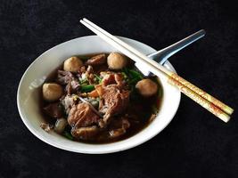 noodle con carne di manzo e polpette in ciotola bianca, zuppa di carne brasata vista dall'alto su sfondo bianco, cucina deliziosa isolata con tracciato di ritaglio foto