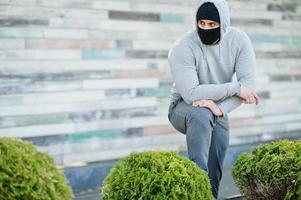 ritratto sportivo uomo arabo in maschera medica nera e felpa con cappuccio durante la quarantena del coronavirus. foto