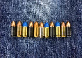 Proiettili di pistola da 9 mm su blue jeans, messa a fuoco morbida e selettiva, vari concetti di raccolta di proiettili. foto
