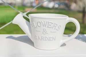 vaso di fiori in ceramica bianca a forma di annaffiatoio sullo scaffale all'aperto, giardino o decorazione d'interni. foto