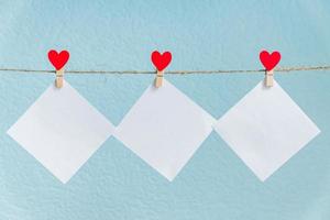 carte bianche su spille con cuori rossi. mockup per testo e sfondo blu per i saluti di San Valentino foto