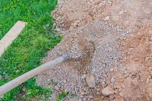 operaio che mescola cemento e ghiaia con una vanga sulla città di costruzione foto