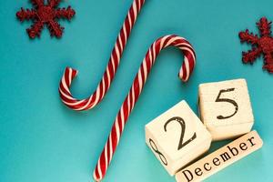 calendario a blocchi di legno che mostra il 25 dicembre. vacanze di Natale. biglietto di auguri con bastoncini di zucchero e fiocchi di neve scintillanti. foto