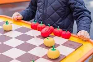 ragazzino in giacca a vento blu che gioca a dama di zucca con un uomo all'aperto foto