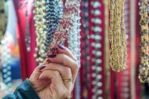 donna che sceglie collane di perle di cristallo colorate. motivo di sfondo. artigianato alla moda per le donne foto