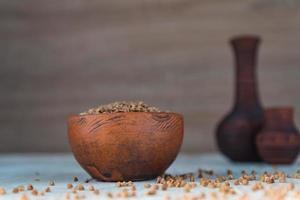 grano saraceno secco in una ciotola di argilla marrone sul tavolo di legno. cereali senza glutine per una dieta sana foto