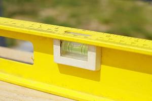 livello dell'edificio giallo. strumento di lavoro su fondo in legno foto