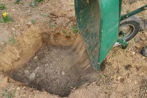 il giardiniere fa una buca nel terreno per piantare alberi foto