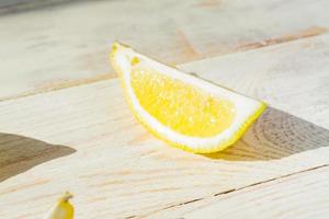 primo piano di un quarto di limone sul tavolo di legno. ombre dure in una giornata di sole foto