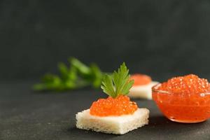 caviale rosso su pane di frumento su sfondo nero, frutti di mare. alimentazione e dieta sana. copia spazio per il testo foto