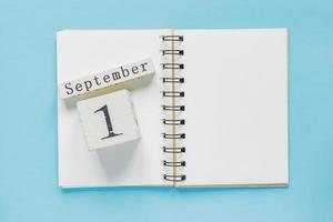 1 settembre su un calendario di legno sul libro di testo di studio su sfondo blu. concetto di ritorno a scuola foto