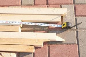 il lavoratore misura le travi di legno sui lavori di costruzione del pavimento di piastrelle foto