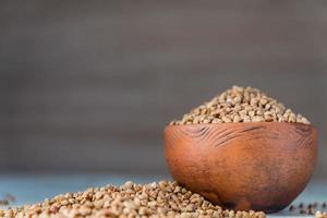 grano saraceno secco in una ciotola di argilla marrone sul tavolo di legno. cereali senza glutine per una dieta sana foto
