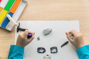 mani di un ragazzino che gioca con l'argilla da modellare colorata. modanatura creativa per bambini a casa. foto
