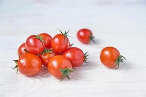 pomodorini freschi su tavola di legno bianca. verdure biologiche, cibo sano e dietetico, soft focus foto