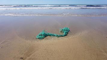 corda di plastica verde sulla spiaggia, inquinamento da plastica foto