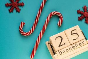 calendario a blocchi di legno che mostra il 25 dicembre. vacanze di Natale. biglietto di auguri con bastoncini di zucchero e fiocchi di neve scintillanti. foto