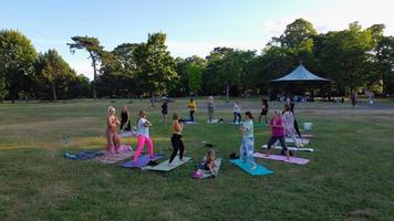 Gruppo di donne che esercitano yoga insieme nel parco pubblico al tramonto di una calda estate, vista aerea ad angolo alto del Wardown Park luton England Regno Unito foto