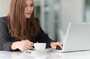 donna dell'Asia in caffè con il computer portatile e caffè, concetto di affari foto