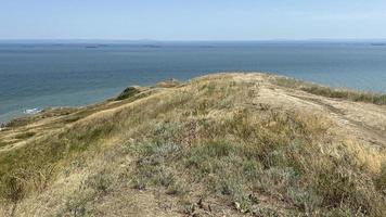 paesaggio marino che domina le colline con erba secca foto