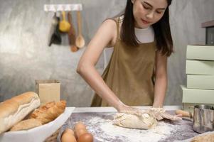 la giovane bella donna sta cuocendo nella sua attività di cucina, panetteria e caffetteria foto